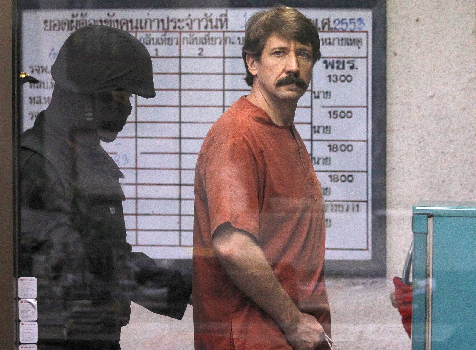 Bout from Russia is escorted by a member of the special police unit as he arrives at a criminal court in Bangkok
